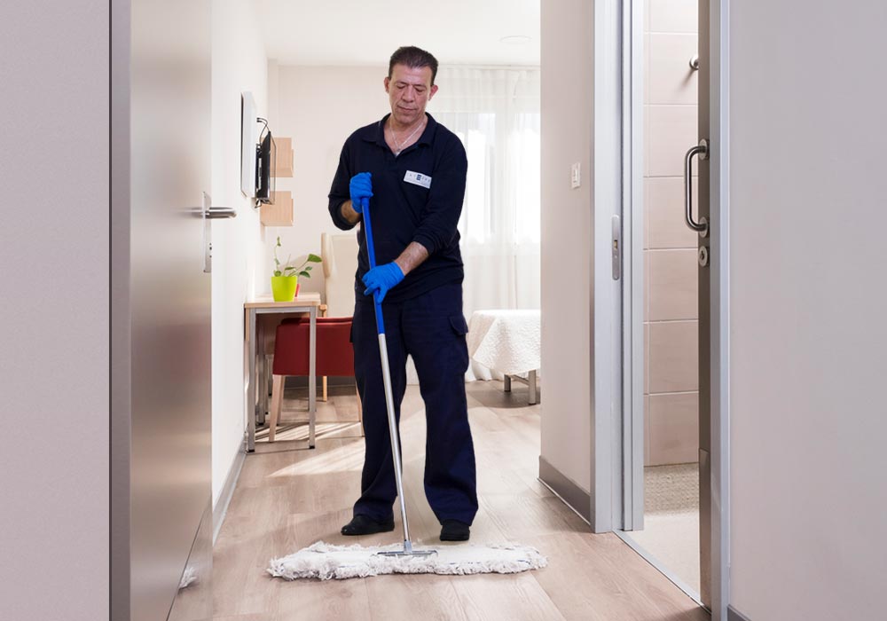 Un limpiador de CleceVitam pasando la mopa en una de las habitaciones de la residencia